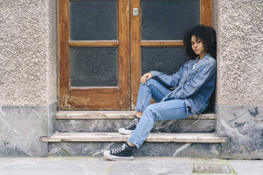 Young woman sitting on steps by door - DGOF02308