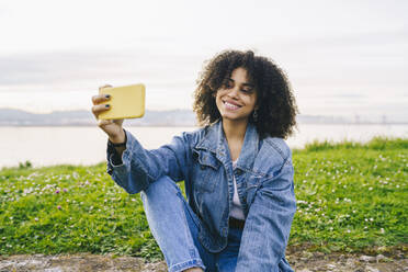 Smiling woman taking selfie on smart phone in nature - DGOF02326