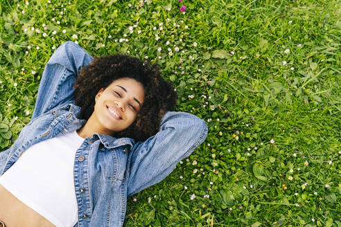 Smiling woman relaxing on grass - DGOF02331