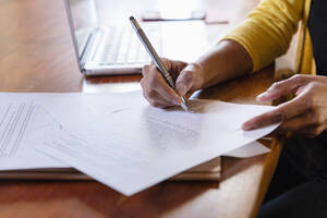 Freelancer signing paper document on desk at home - EIF03496