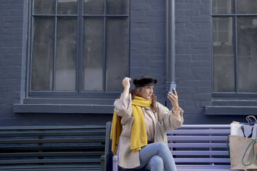 Woman taking selfie with beret on bench - AMWF00184