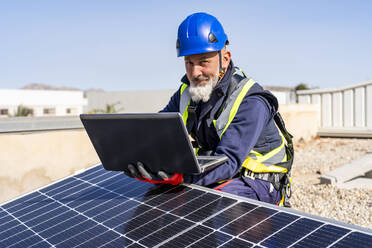 Lächelnder Techniker mit Laptop bei der Arbeit im Solarkraftwerk - DLTSF02733