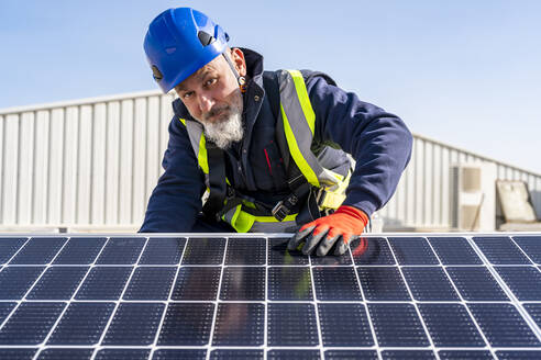 Technician with helmet by solar panel on sunny day - DLTSF02737