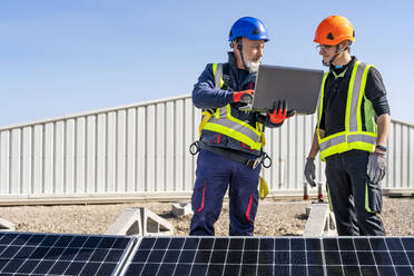 Techniker mit Laptop bespricht sich mit einem Kollegen im Solarkraftwerk - DLTSF02738