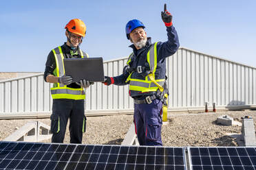 Ingenieur zeigt auf einen Techniker mit Laptop im Solarkraftwerk - DLTSF02739