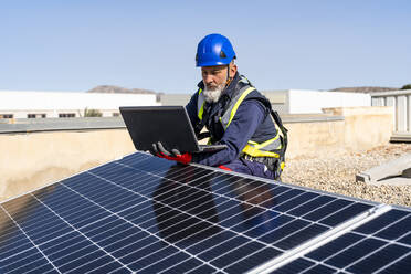 Techniker mit Laptop bei der Arbeit im Solarkraftwerk - DLTSF02741
