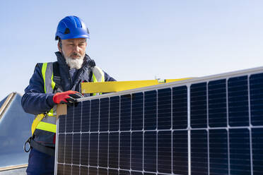 Techniker mit Helm bei der Arbeit mit einem Solarpanel - DLTSF02743