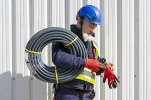 Ingenieur mit Kabeln und Schutzhandschuh an einem sonnigen Tag - DLTSF02745