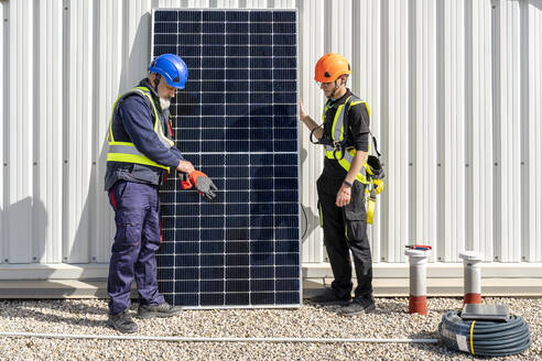 Kollegen stehen vor einem Solarpanel im Kraftwerk - DLTSF02749