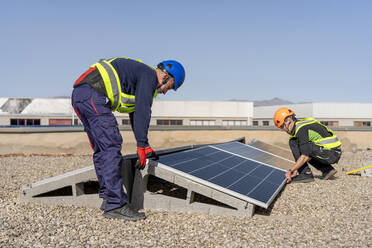 Ingenieure bei der Installation von Solarmodulen an einem sonnigen Tag - DLTSF02755