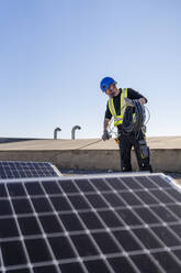 Ingenieur rollt an einem sonnigen Tag Kabel im Solarkraftwerk auf - DLTSF02766