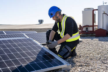 Techniker bei der Prüfung von Solarmodulen an einem sonnigen Tag - DLTSF02767
