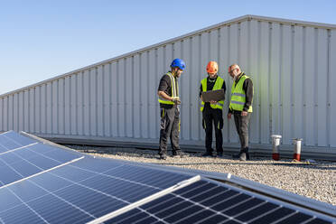 Techniker diskutieren über Laptop im Solarkraftwerk - DLTSF02772