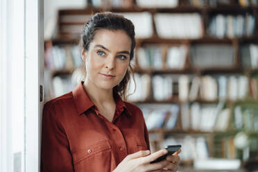 Woman holding mobile phone in cafe - KNSF09347