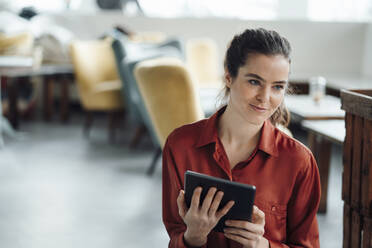 Smiling woman with tablet computer contemplating in cafe - KNSF09351