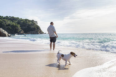 Mann am Strand mit Hund am Wochenende - KMKF01786