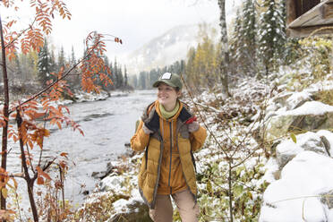 Smiling hiker walking near river in winter forest - VBUF00021