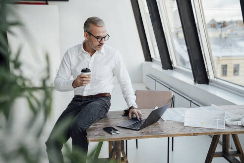 Geschäftsmann mit Laptop auf dem Schreibtisch im Büro - VPIF05479