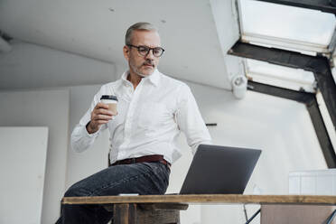 Architect using laptop sitting on desk in office - VPIF05480