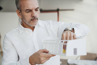 Architect examining architectural model at work place - VPIF05489