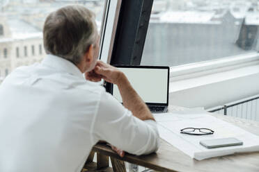 Businessman using laptop at work place - VPIF05519