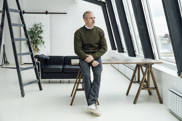 Contemplative businessman leaning on desk in startup office - VPIF05522