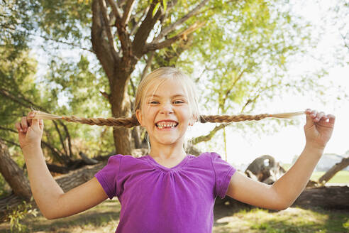 Little girl (4-5) holding out her pig tails as far as she can - TETF00022