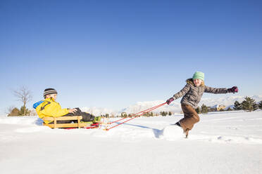 Children (8-9) playing with sled in snow - TETF00037