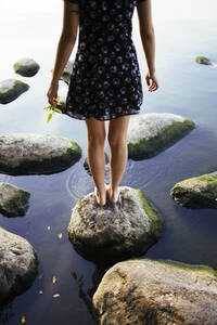 Barfüßige Frau steht auf einem Felsen im Meer - TETF00050