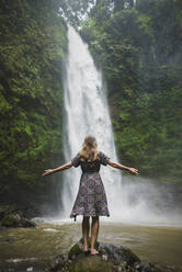 Woman standing by waterfall in Bali, Indonesia - TETF00061
