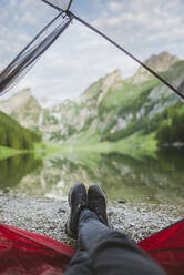 Die Füße einer Frau ragen aus dem Zelt am Seealpsee in den Appenzeller Alpen, Schweiz - TETF00063