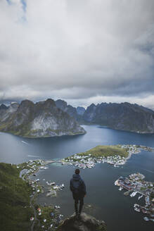 Norwegen, Lofoten, Reine, Mann schaut vom Reinebringen auf den Fjord - TETF00088