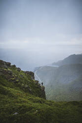 Norwegen, Lofoten, Reine, Mann betrachtet Aussicht vom Berg Reinebringen bei Regen - TETF00089