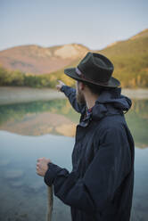 Italy, Man pointing towards mountains - TETF00092