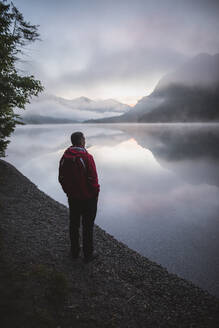 Österreich, Plansee, Junger Mann steht am Plansee bei Sonnenaufgang - TETF00094