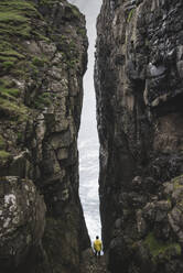 Denmark, Faroe Islands, Sorvagur, Man standing between two cliffs - TETF00100