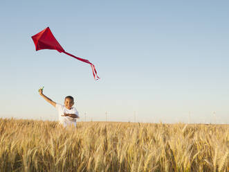 Boy (10-11) playing with kite in wheat field - TETF00119