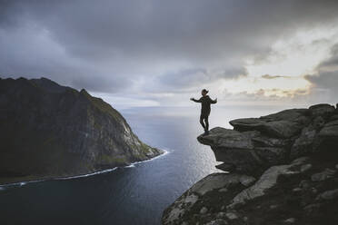 Mann steht auf einer Klippe am Berg Ryten auf den Lofoten, Norwegen - TETF00178