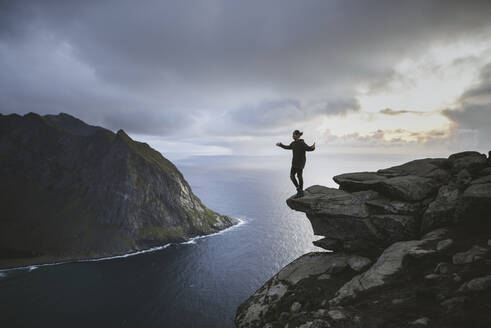 Man standing on cliff at Ryten mountain in Lofoten Islands, Norway - TETF00178