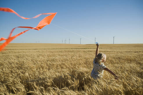 Girl running with kite on wind farm - TETF00231
