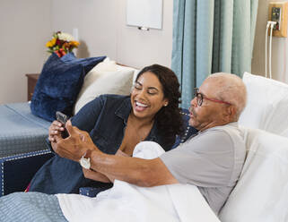 Smiling woman and smiling senior man looking at smart phone - TETF00315