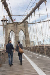 Paar hält sich an den Händen und läuft auf der Brooklyn Bridge - TETF00331