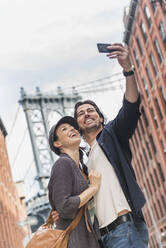 Pärchen macht Selfie auf der Straße, Brooklyn Bridge im Hintergrund - TETF00335
