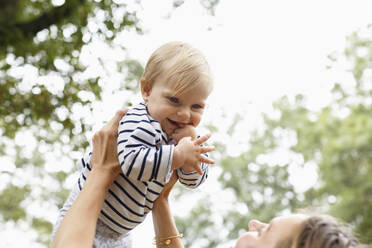 Mutter hält Baby in der Luft, lächelnd - TETF00343