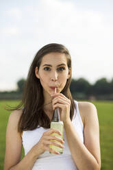 Junge Frau trinkt Limonadensaft im Park - MIKF00085