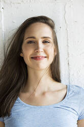 Smiling brunette woman in front of wall - MIKF00087