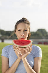 Junge Frau mit Wassermelonenscheibe an einem sonnigen Tag - MIKF00090