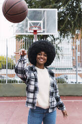 Young woman throwing basketball standing on sports court - PNAF03336