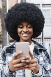 Happy afro woman text messaging through smart phone - PNAF03338