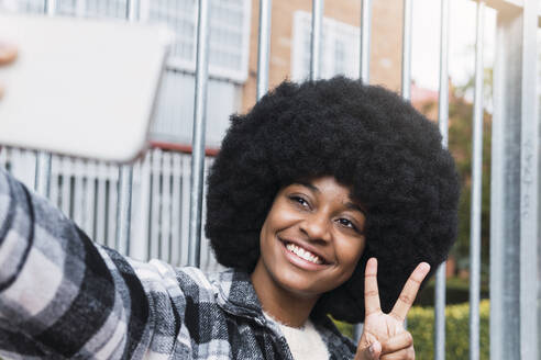 Glückliche Frau nimmt Selfie mit Friedenszeichen - PNAF03339